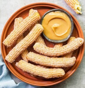 A small dish of dulce de leche with churros